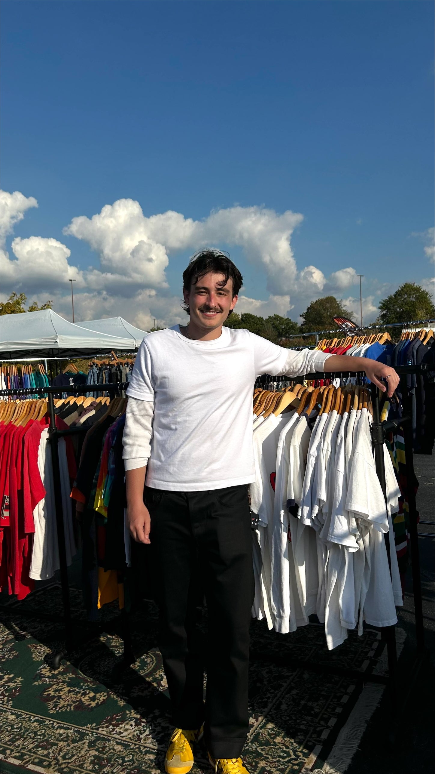 Andrew Martinez of Stitch Revivals standing between racks of clothes at a Pop-up